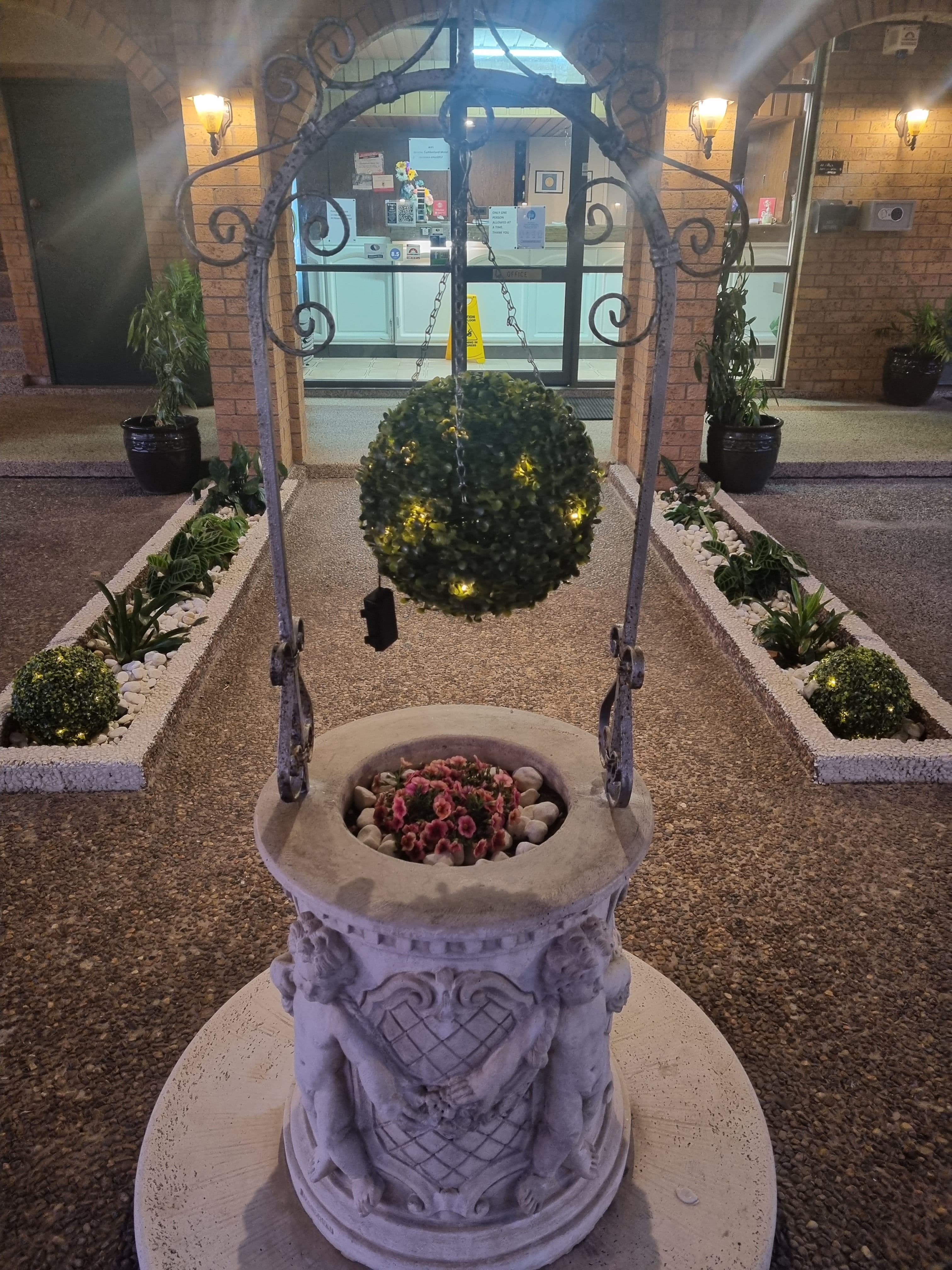 Landscaped garden flowerbed and wishing well at Cumberland Motor Inn